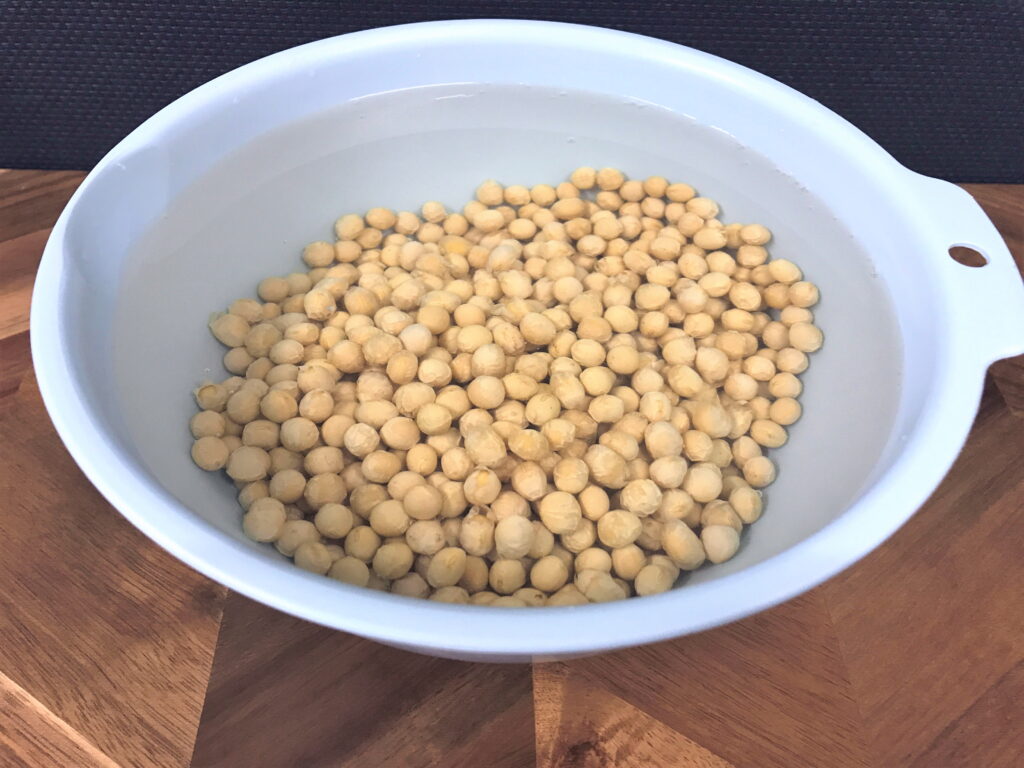 乾燥大豆をボウルに入れられた水で戻す