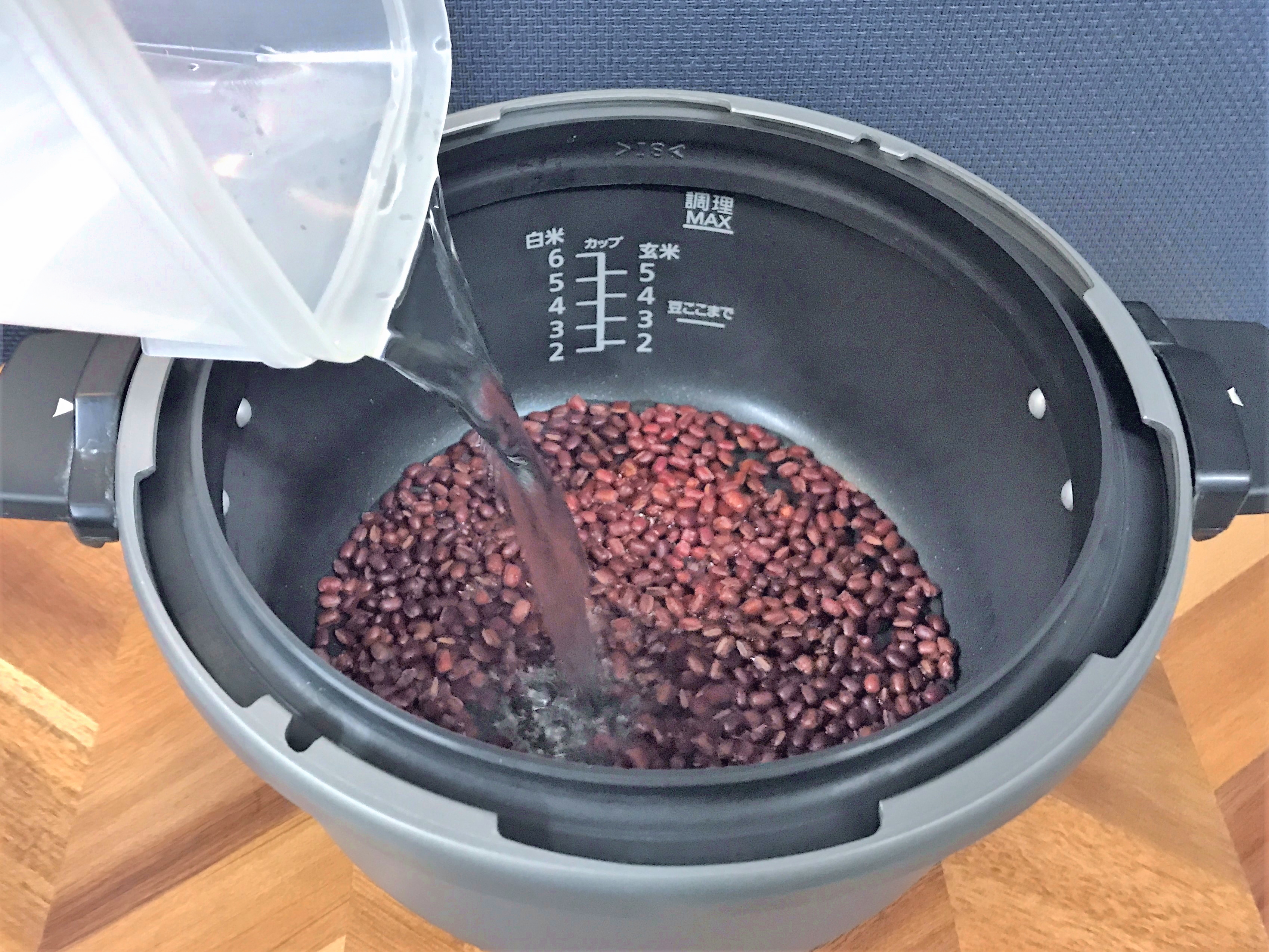 小豆を入れた圧力鍋に水を注ぐ